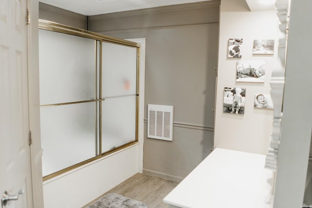 bathroom with bath / shower combo with glass door, visible vents, baseboards, and wood finished floors