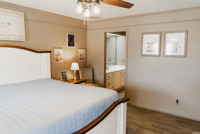 bedroom with baseboards, ensuite bath, dark wood-type flooring, crown molding, and a sink