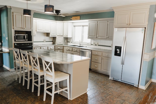 kitchen with a breakfast bar, tile counters, stainless steel appliances, and decorative backsplash