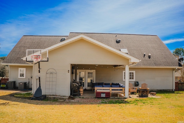 back of property featuring a lawn, an outdoor living space with a fire pit, roof with shingles, cooling unit, and a patio area