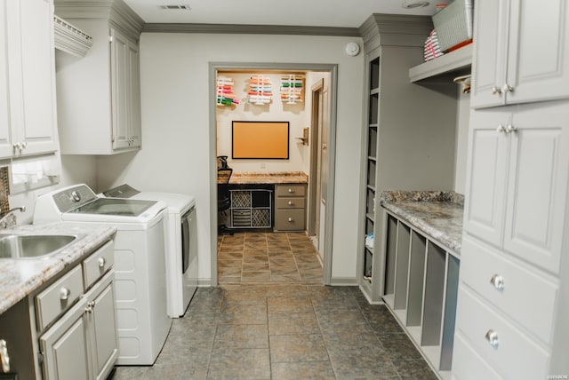 clothes washing area with cabinet space, stone finish floor, crown molding, separate washer and dryer, and a sink