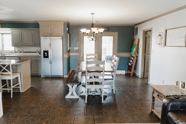 dining space featuring a chandelier, stone finish flooring, ornamental molding, and baseboards