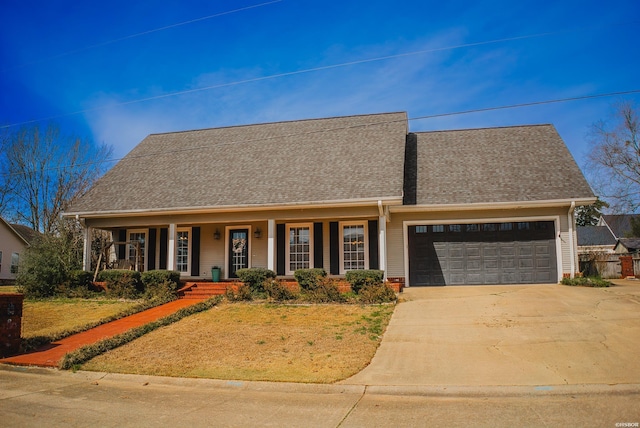 view of front of property featuring a garage, covered porch, driveway, and roof with shingles