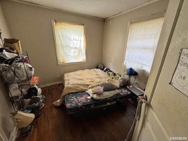 bedroom with a textured ceiling, ornamental molding, dark wood-style flooring, and baseboards