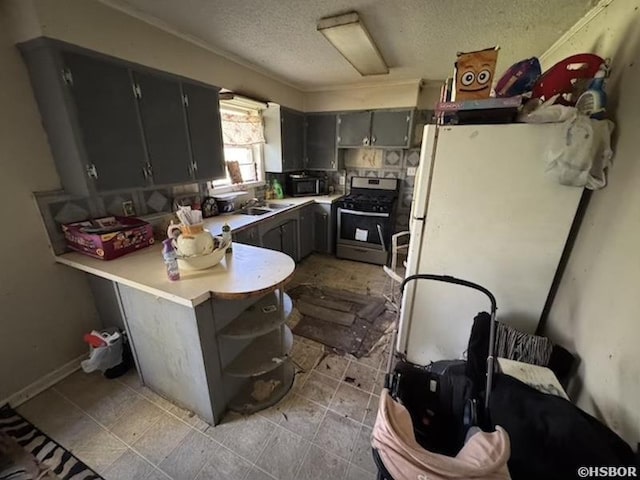 kitchen featuring stainless steel gas stove, freestanding refrigerator, a peninsula, light countertops, and black microwave