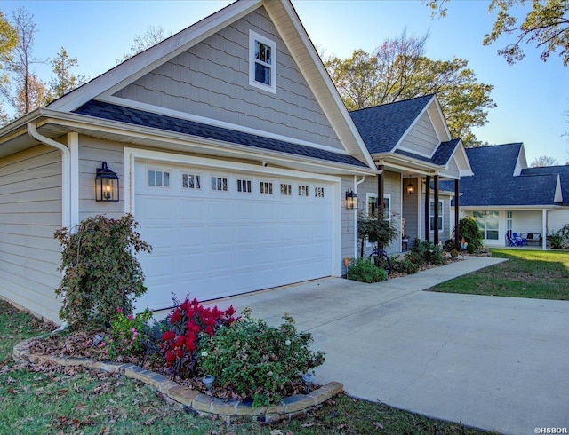 view of front of house with a garage, concrete driveway, and roof with shingles