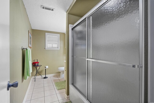 bathroom featuring a textured ceiling, toilet, visible vents, baseboards, and tile patterned floors