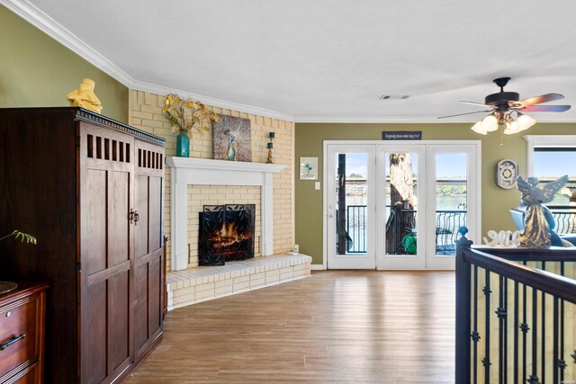 living area with ornamental molding, a brick fireplace, a healthy amount of sunlight, and light wood finished floors