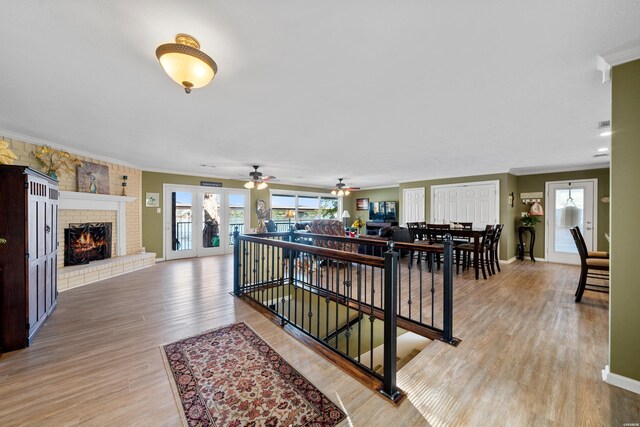 hall featuring light wood-style flooring, baseboards, and crown molding