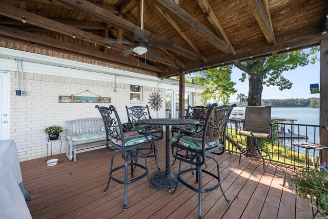 deck with a ceiling fan, outdoor dining area, and a water view