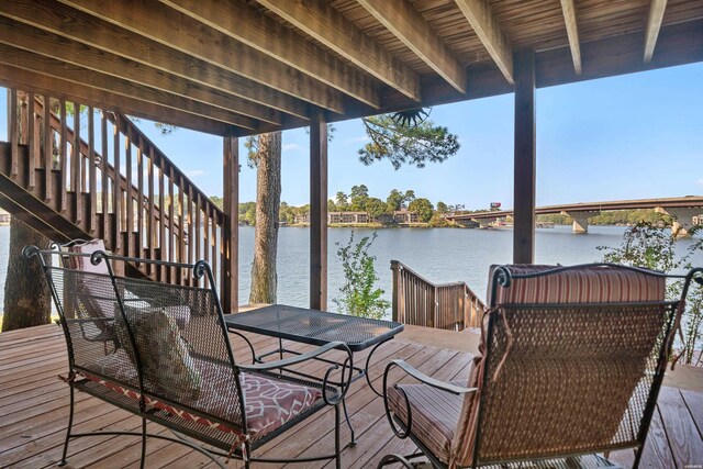 wooden terrace with a water view and stairs