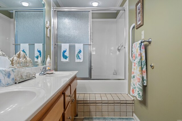 full bathroom with double vanity, shower / bath combination with glass door, and a sink