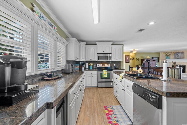 kitchen with light wood-style flooring, stainless steel appliances, a sink, visible vents, and white cabinets