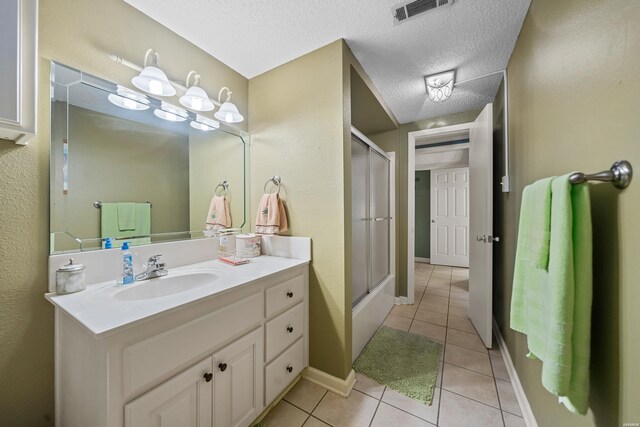 full bath with visible vents, an enclosed shower, a textured ceiling, vanity, and tile patterned flooring