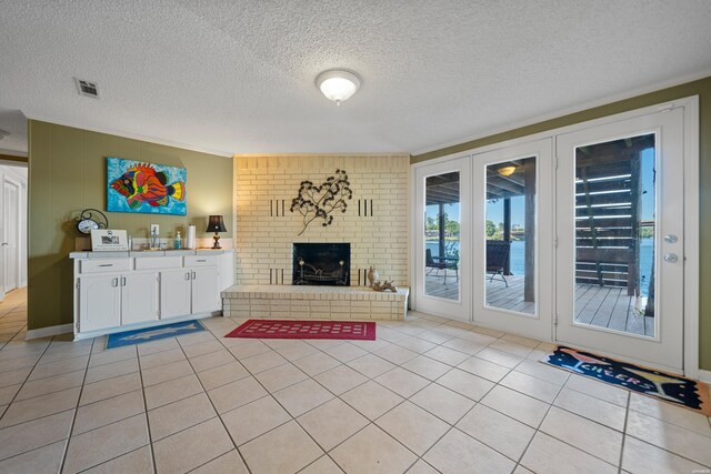 living room with light tile patterned floors, a textured ceiling, a fireplace, and visible vents