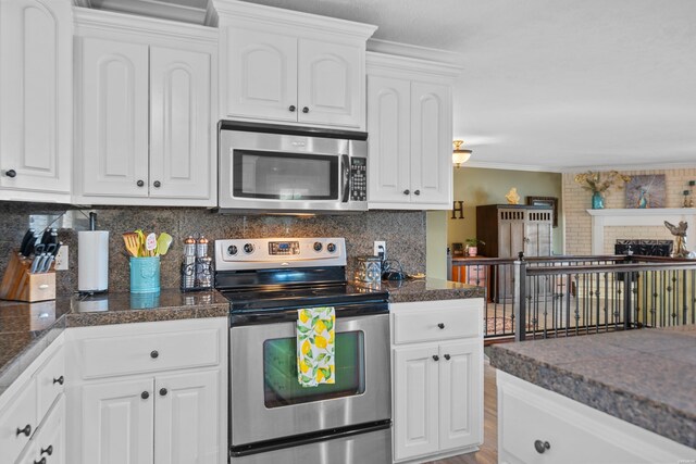 kitchen with crown molding, tile countertops, stainless steel appliances, tasteful backsplash, and white cabinetry