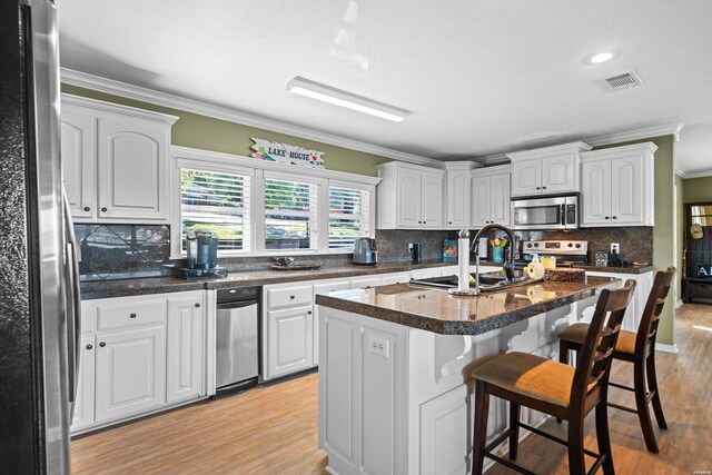 kitchen featuring white cabinets, a kitchen island with sink, stainless steel appliances, and a sink