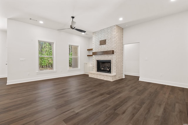 unfurnished living room featuring dark wood-style floors, baseboards, recessed lighting, a brick fireplace, and ceiling fan