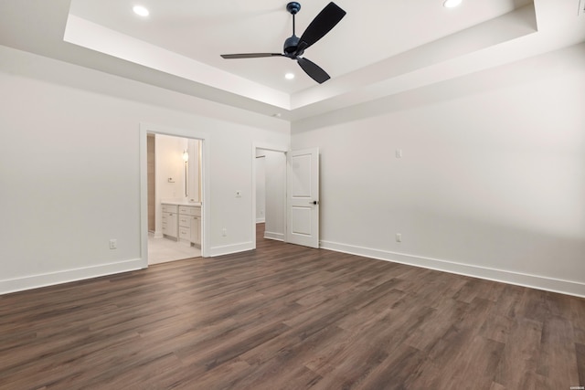unfurnished bedroom with recessed lighting, a raised ceiling, baseboards, and dark wood-style floors