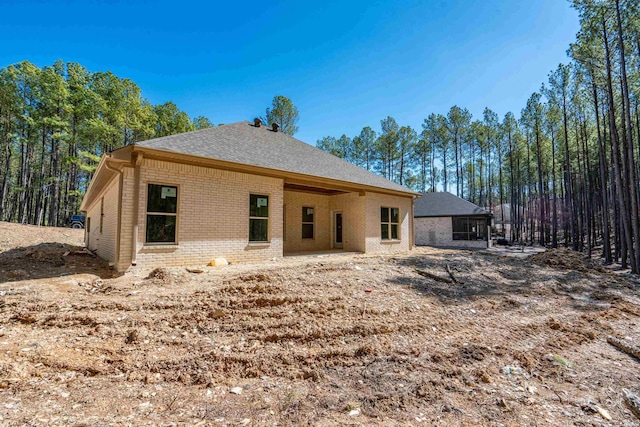 back of property with a shingled roof and brick siding