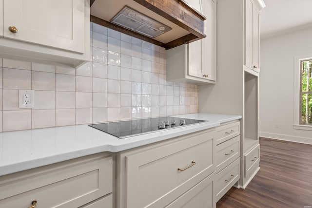 kitchen featuring light countertops, black electric cooktop, wall chimney exhaust hood, and decorative backsplash