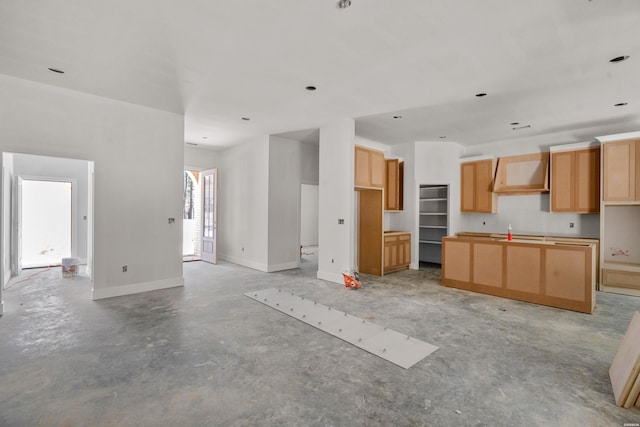 kitchen with open floor plan, a kitchen island, concrete floors, baseboards, and exhaust hood