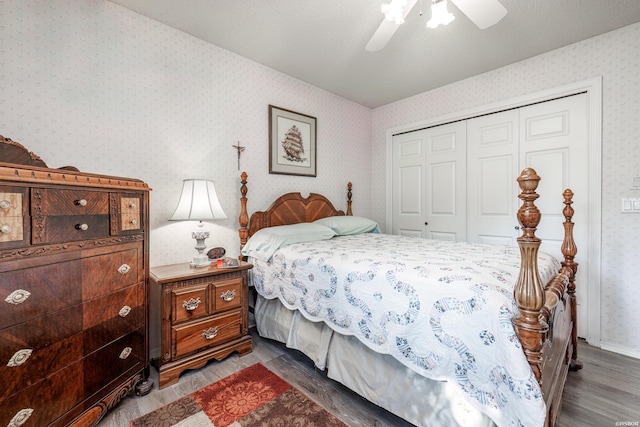 bedroom with ceiling fan, a textured ceiling, a closet, dark wood-style floors, and wallpapered walls