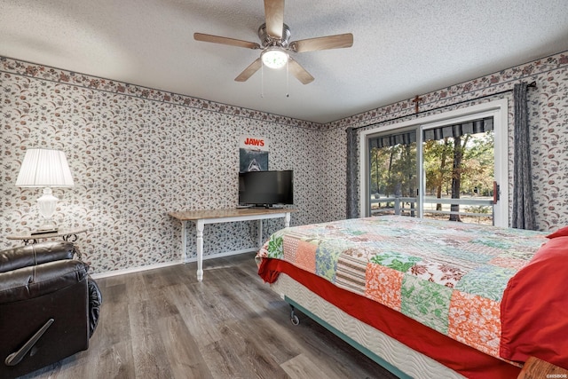 bedroom with wallpapered walls, a textured ceiling, and wood finished floors