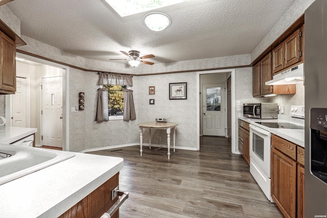 kitchen featuring stainless steel appliances, brown cabinetry, light countertops, and under cabinet range hood