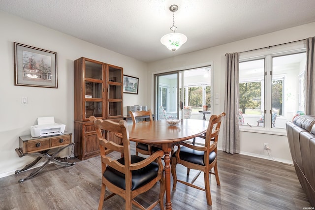 dining space featuring dark wood-style floors, a textured ceiling, and baseboards