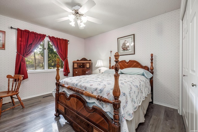 bedroom featuring wallpapered walls, baseboards, dark wood-type flooring, a textured ceiling, and a closet