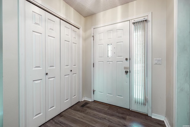 entrance foyer with dark wood-style floors, baseboards, visible vents, and a textured ceiling