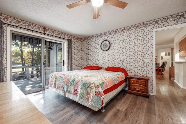 bedroom featuring wallpapered walls, access to exterior, a textured ceiling, and wood finished floors