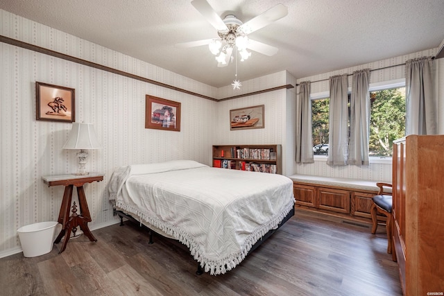 bedroom with wallpapered walls, baseboards, dark wood-style flooring, and a textured ceiling