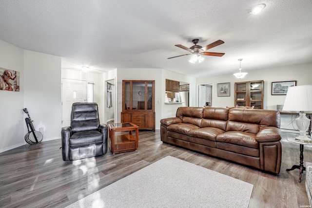 living area with a textured ceiling, wood finished floors, a ceiling fan, and baseboards