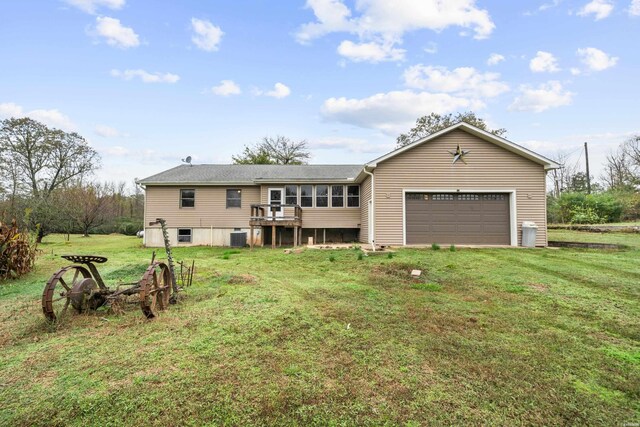 back of property featuring driveway, an attached garage, cooling unit, and a lawn