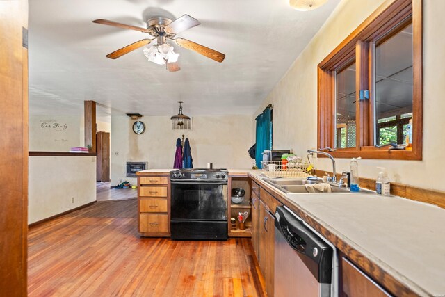 kitchen with light wood finished floors, range with gas stovetop, dishwasher, light countertops, and a sink