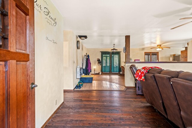 living room featuring dark wood-type flooring, a ceiling fan, and baseboards