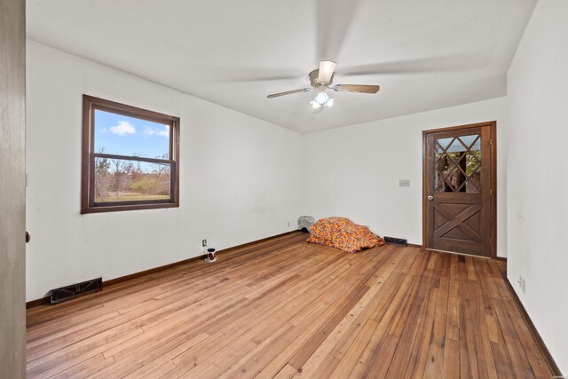 spare room featuring light wood-style floors, plenty of natural light, and visible vents