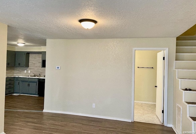 spare room with dark wood-style floors, a textured ceiling, baseboards, and a sink