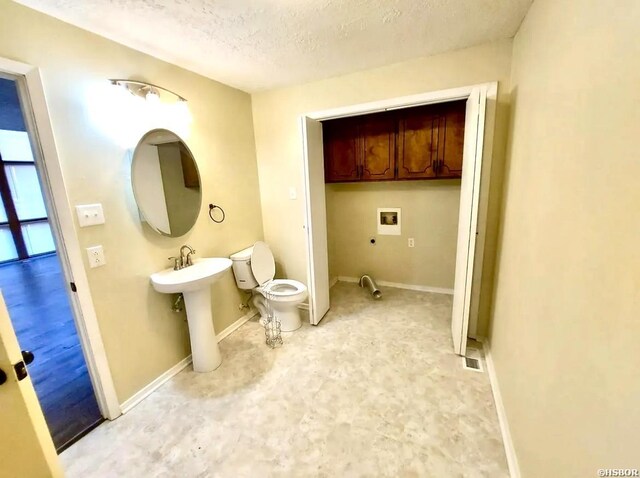 bathroom with toilet, a sink, baseboards, and a textured ceiling