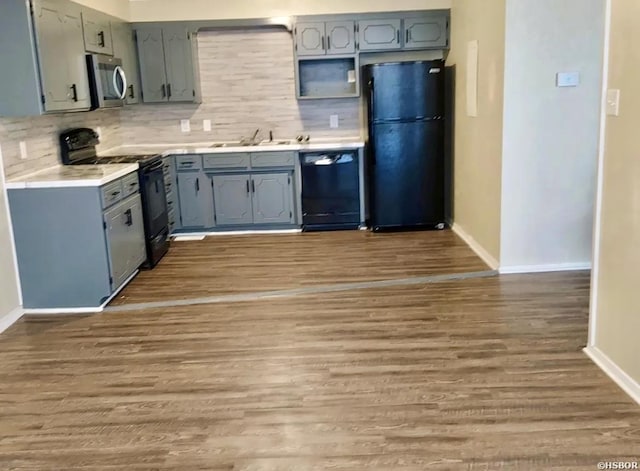 kitchen with gray cabinetry, a sink, light countertops, dark wood-style floors, and black appliances