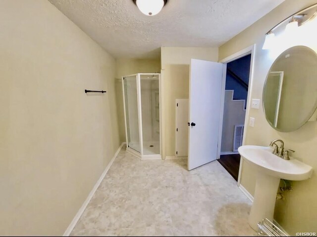 bathroom featuring a shower stall, visible vents, a textured ceiling, and baseboards