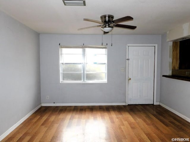 empty room featuring wood finished floors, visible vents, baseboards, and ceiling fan