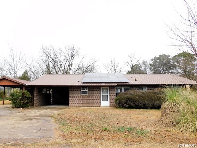 ranch-style home featuring a carport, metal roof, brick siding, and driveway