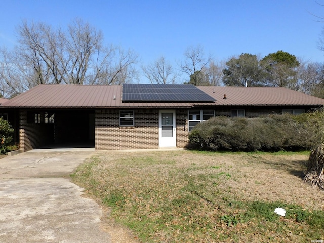 single story home featuring a front yard, concrete driveway, an attached carport, roof mounted solar panels, and metal roof