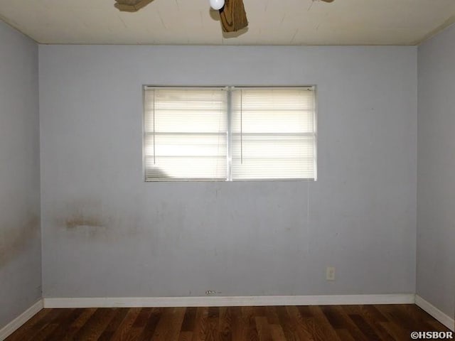 empty room featuring dark wood-style floors, baseboards, and ceiling fan