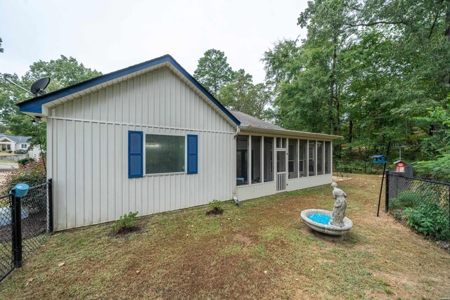 back of property with a sunroom, fence, and a yard