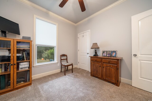 living area featuring baseboards, ornamental molding, a ceiling fan, and light colored carpet