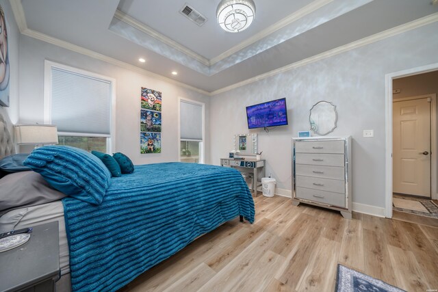 bedroom featuring light wood finished floors, a raised ceiling, visible vents, and crown molding